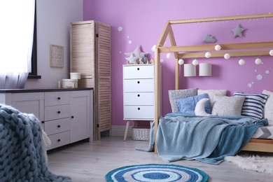 Photo of Child's room interior with comfortable bed and garland