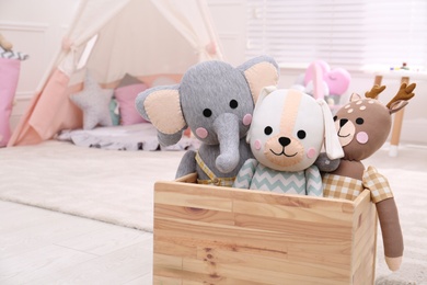 Wooden crate with cute toys in stylish playroom, space for text. Interior design