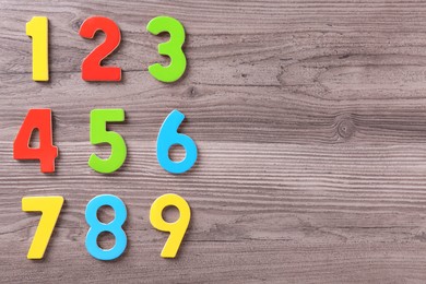 Photo of Colorful numbers on wooden school desk, flat lay. Space for text