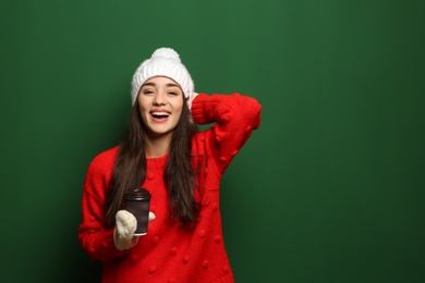 Photo of Young woman in sweater with cup of hot coffee on color background, space for text. Winter season