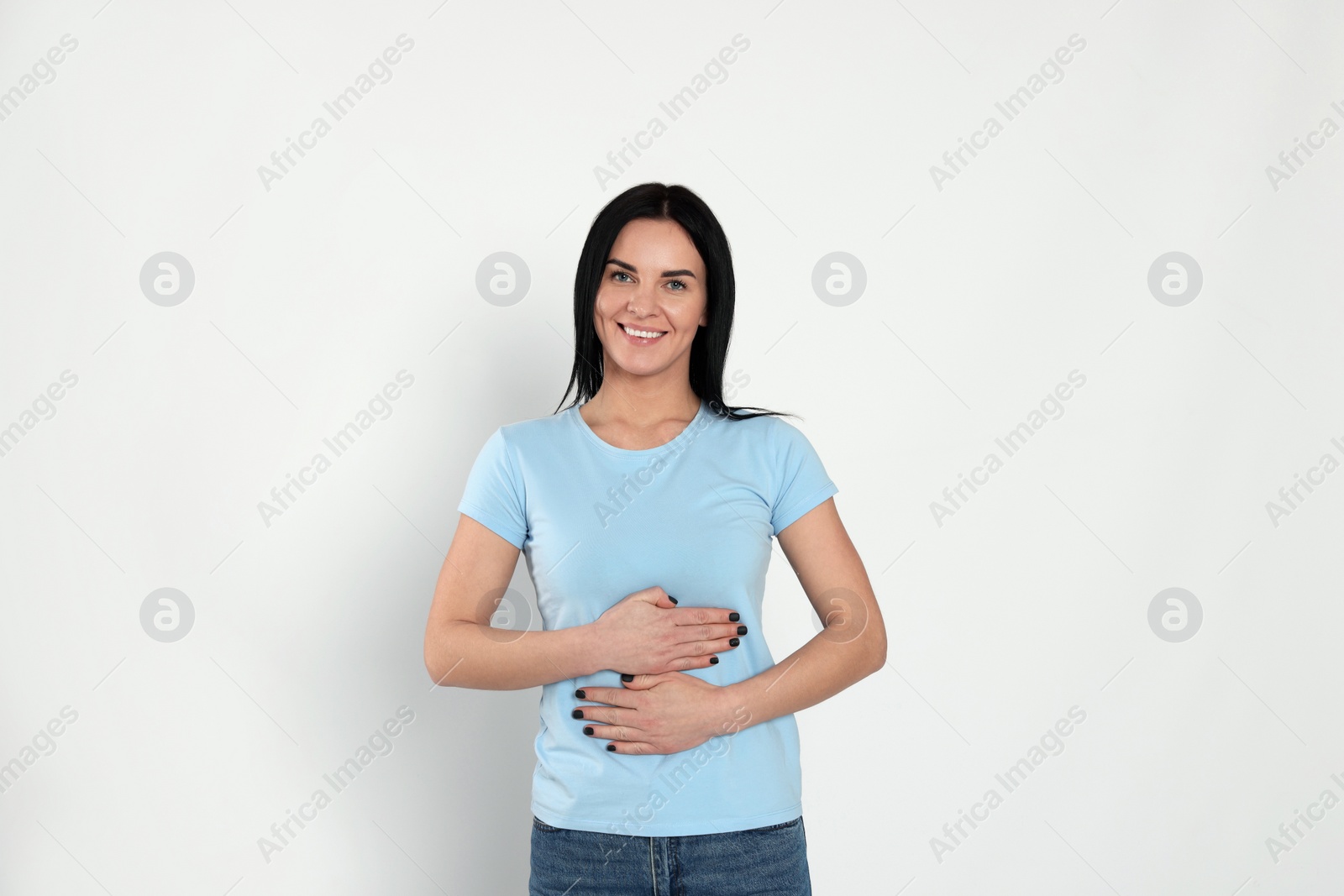 Photo of Happy woman touching her belly on light background. Concept of healthy stomach