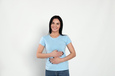 Photo of Happy woman touching her belly on light background. Concept of healthy stomach