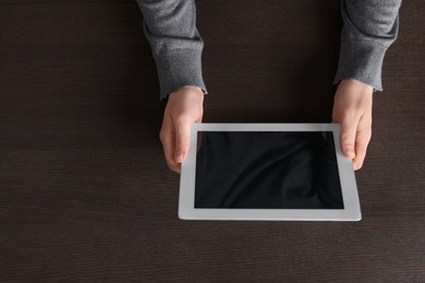 Man working with tablet at wooden table, top view. Space for text