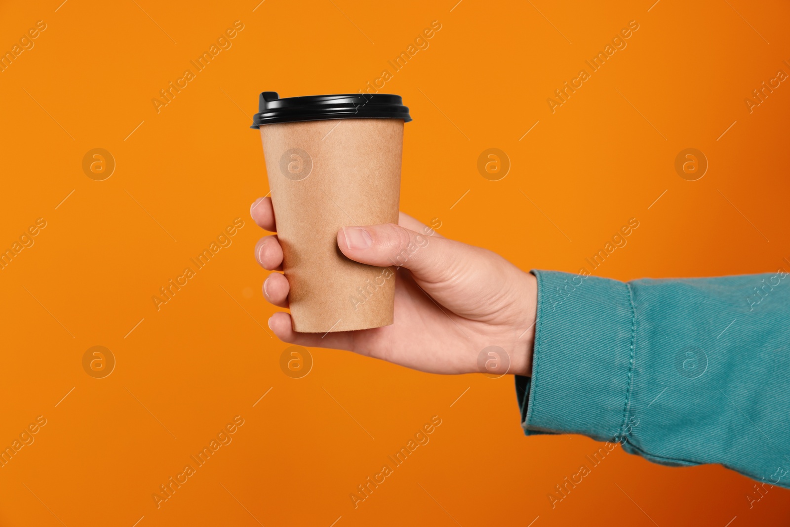 Photo of Woman holding takeaway cup with drink on orange background, closeup. Coffee to go