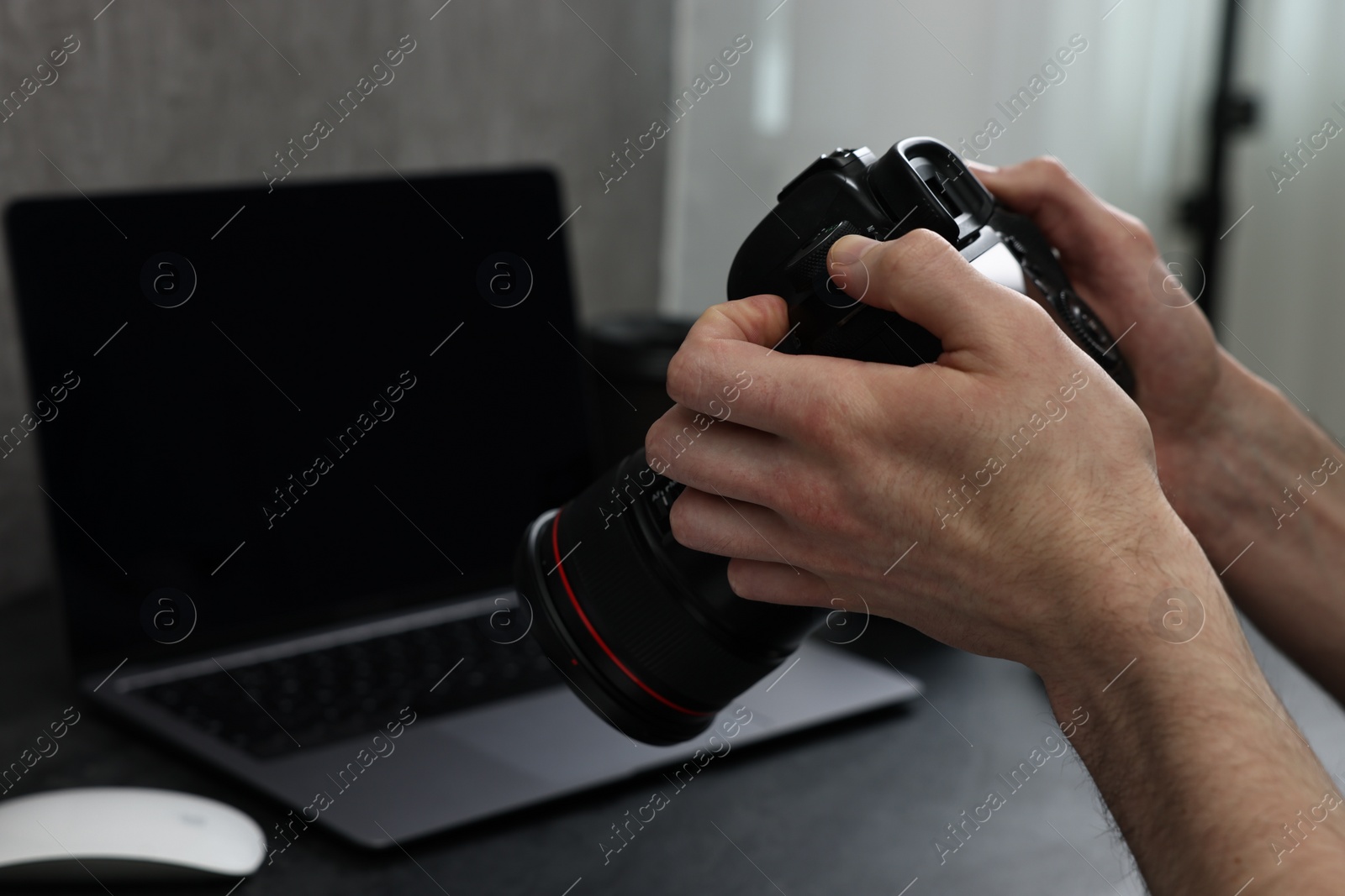 Photo of Photographer holding camera at dark table, closeup