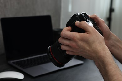 Photo of Photographer holding camera at dark table, closeup