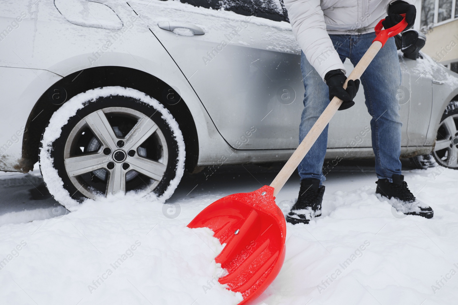 Photo of Man removing snow with shovel near car outdoors, closeup