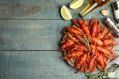 Flat lay composition with delicious red boiled crayfishes on wooden table, space for text