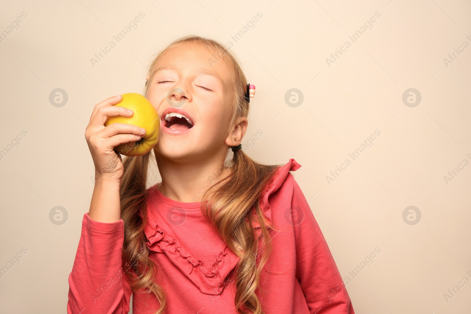 Photo of Cute little girl with apple on light background