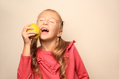 Photo of Cute little girl with apple on light background