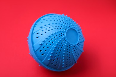 Photo of Dryer ball for washing machine on red background. Laundry detergent substitute