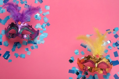 Photo of Beautiful carnival masks and shiny confetti on pink background, flat lay. Space for text