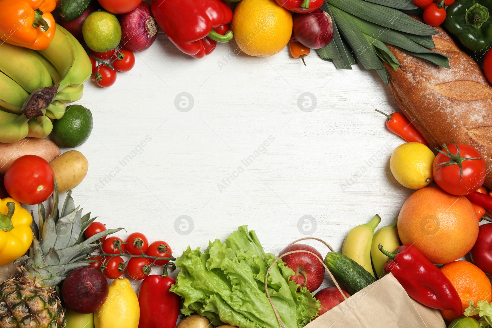 Photo of Frame of paper bag with fresh vegetables and fruits on white wooden background, top view. Space for text