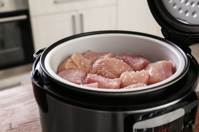 Fresh cut chicken in modern multi cooker on table, closeup