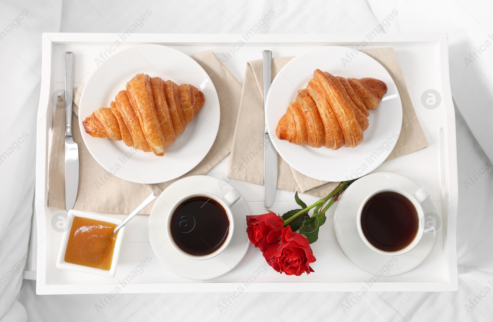 Tasty breakfast served in bed. Fresh croissants, coffee and honey on tray, top view Photo of Tasty breakfast served in bed. Fresh croissants, coffee and honey on tray, top view