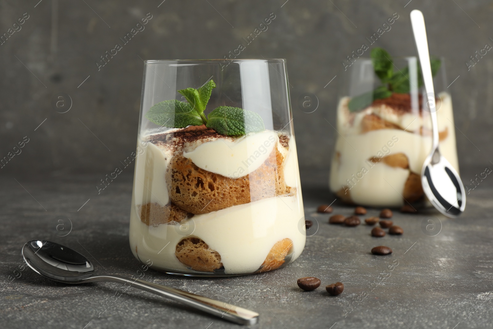 Photo of Delicious tiramisu with mint in glass on grey table