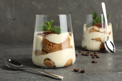 Photo of Delicious tiramisu with mint in glass on grey table