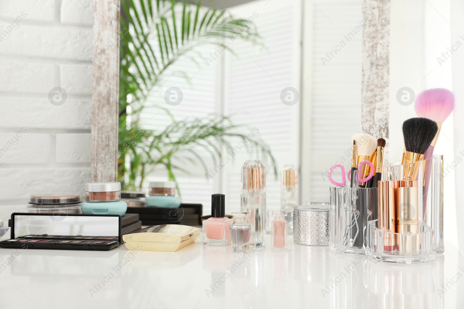 Photo of Luxury makeup products and accessories on dressing table with mirror. Space for text