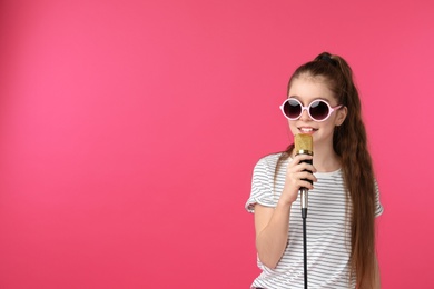 Cute girl with microphone on color background. Space for text