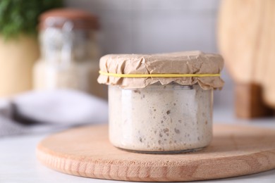 Photo of Sourdough starter in glass jar on table, closeup. Space for text