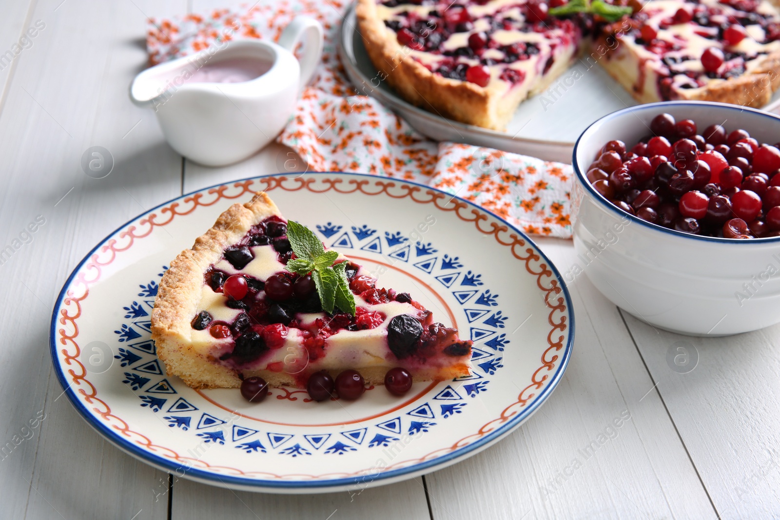 Photo of Piece of delicious currant pie served on white wooden table