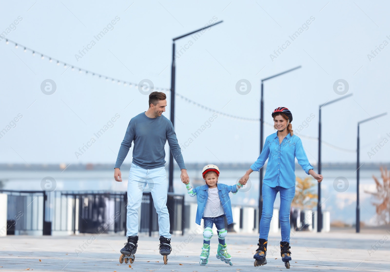 Photo of Happy family roller skating on embankment. Active leisure