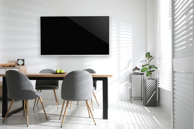 Image of Modern wide screen TV on white wall in room with stylish furniture 