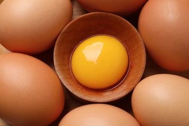 Photo of Chicken eggs and bowl with raw yolk on table, flat lay