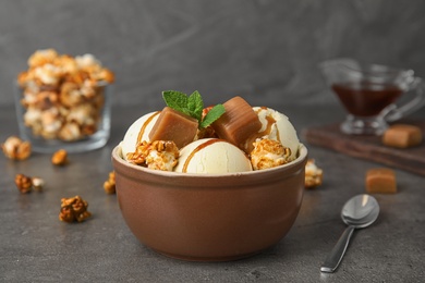Photo of Delicious ice cream with caramel and popcorn in bowl on table