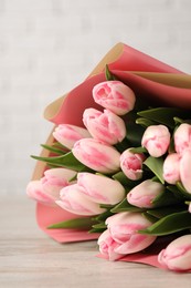 Photo of Beautiful bouquet of fresh pink tulips on light wooden table, closeup