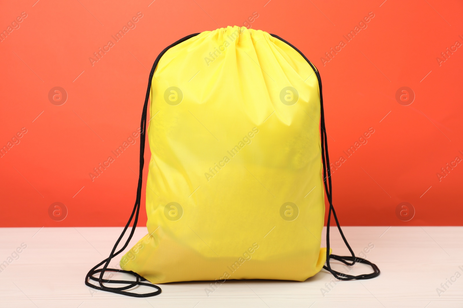 Photo of Yellow drawstring bag on white wooden table