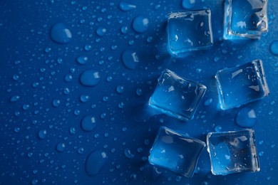 Photo of Ice cubes with water drops on blue background, flat lay. Space for text