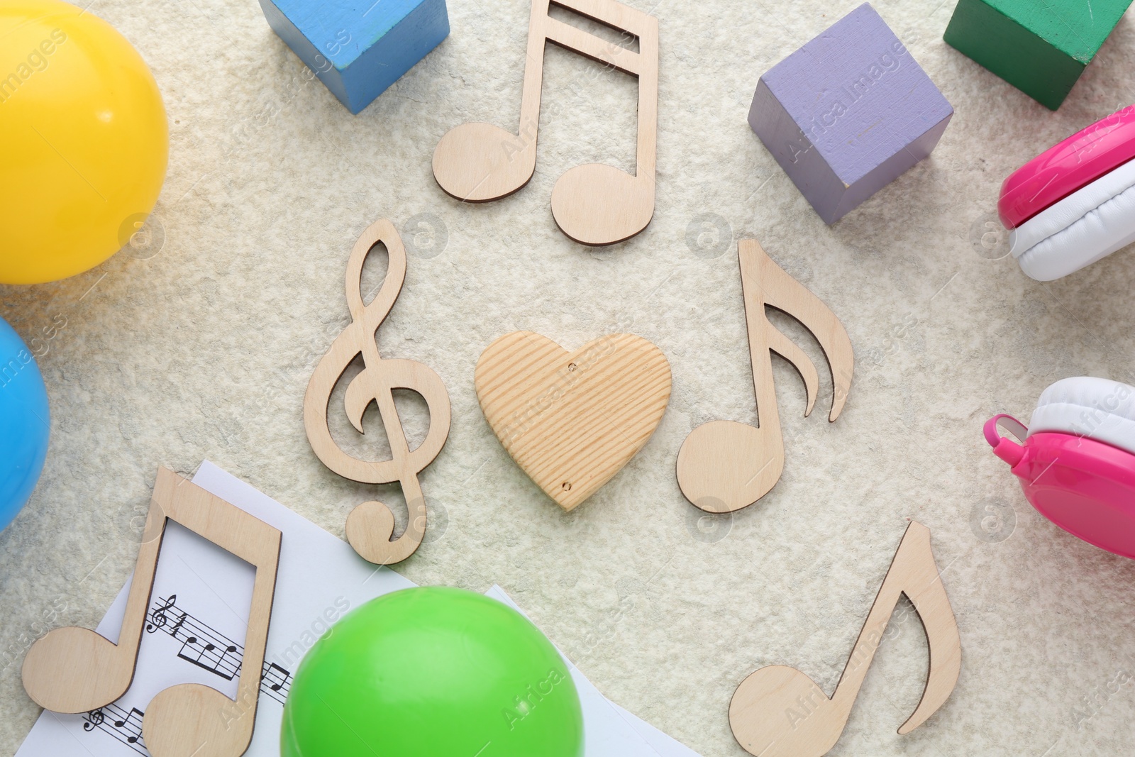 Photo of Wooden notes, music sheet and toys on beige textured background, flat lay. Baby song concept