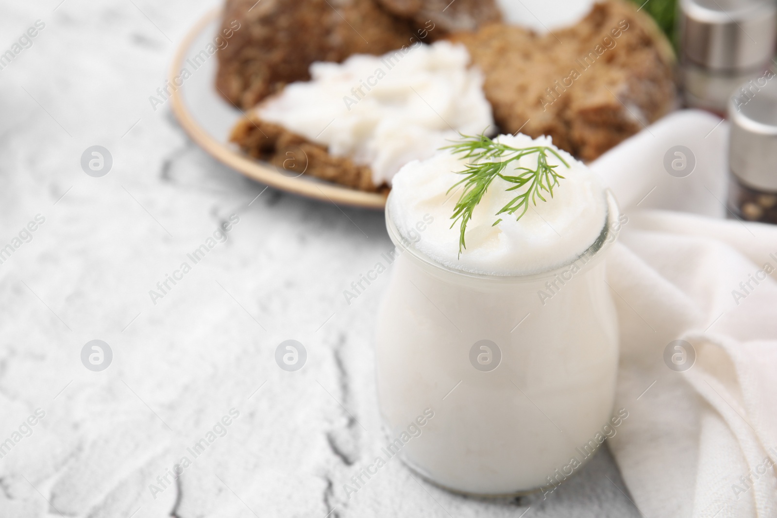 Photo of Delicious pork lard with dill in glass jar on light textured table, closeup. Space for text