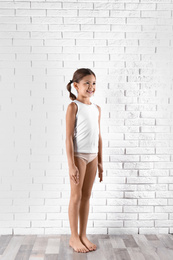 Cute little girl in underwear near white brick wall