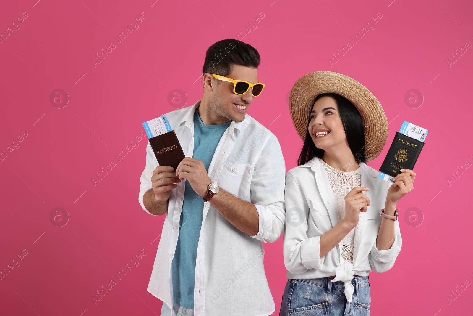 Photo of Couple of tourists with tickets and passports on pink background