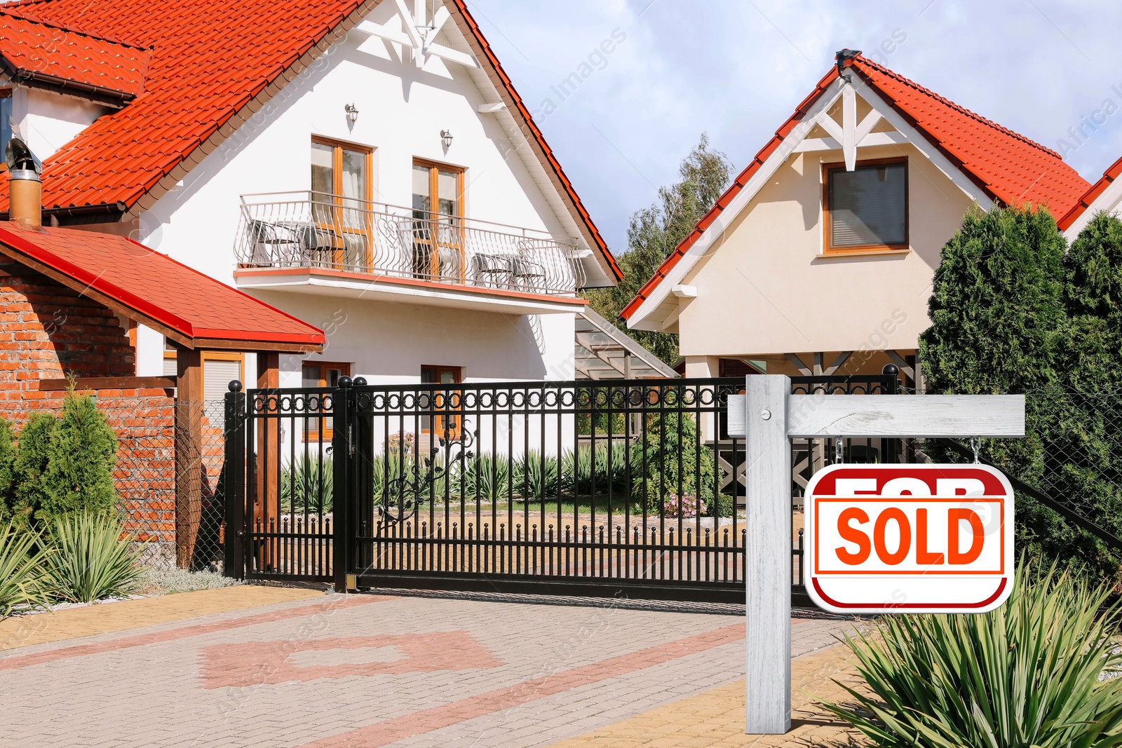 Image of Red sale sign with Sold sticker near house