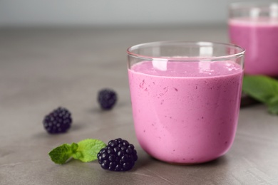 Photo of Glass with blackberry yogurt smoothie on grey table
