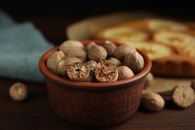 Nutmeg seeds and pie on wooden table, closeup