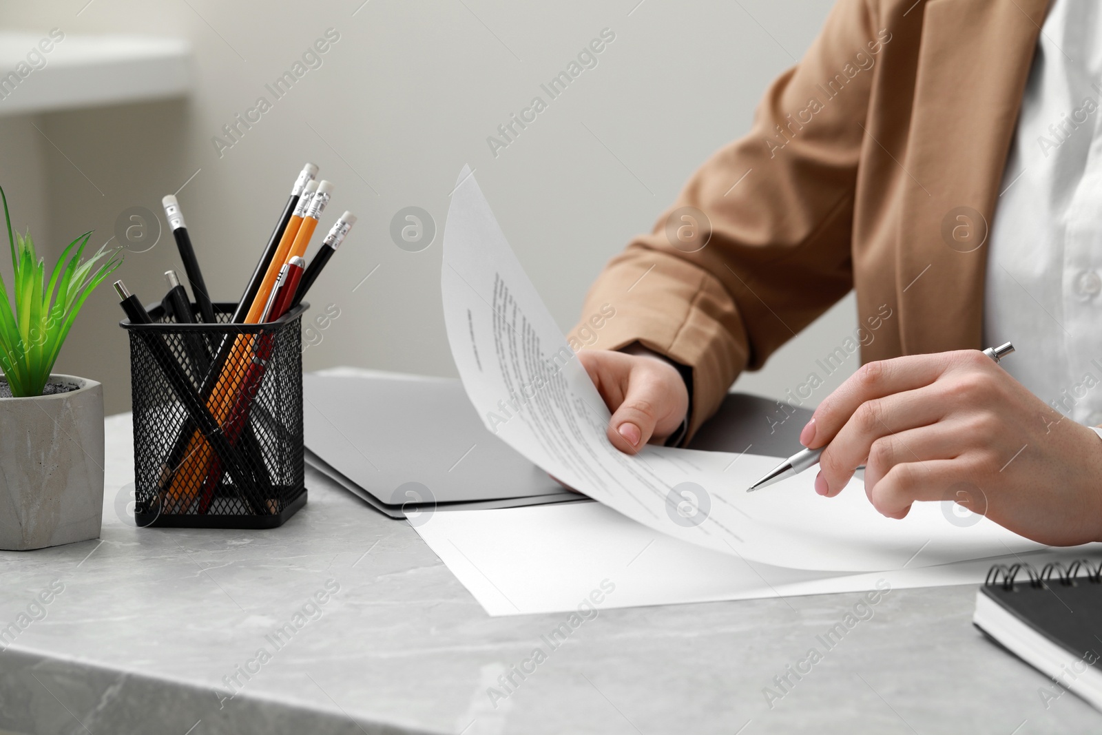 Photo of Woman signing document at light grey marble table in office, closeup