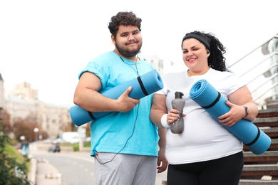 Photo of Overweight couple in sportswear with mats outdoors