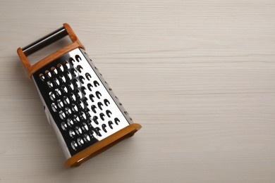 Modern grater on white wooden table, top view. Space for text