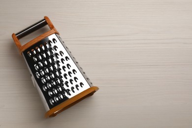 Photo of Modern grater on white wooden table, top view. Space for text