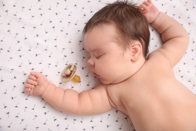 Cute little baby with pacifier sleeping on blanket, top view