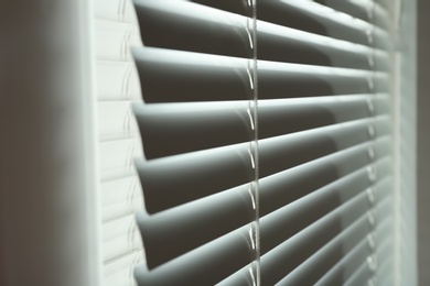 Photo of Closed modern white window blinds, closeup view