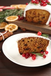 Traditional classic Christmas cake decorated with cranberries and rosemary on wooden table