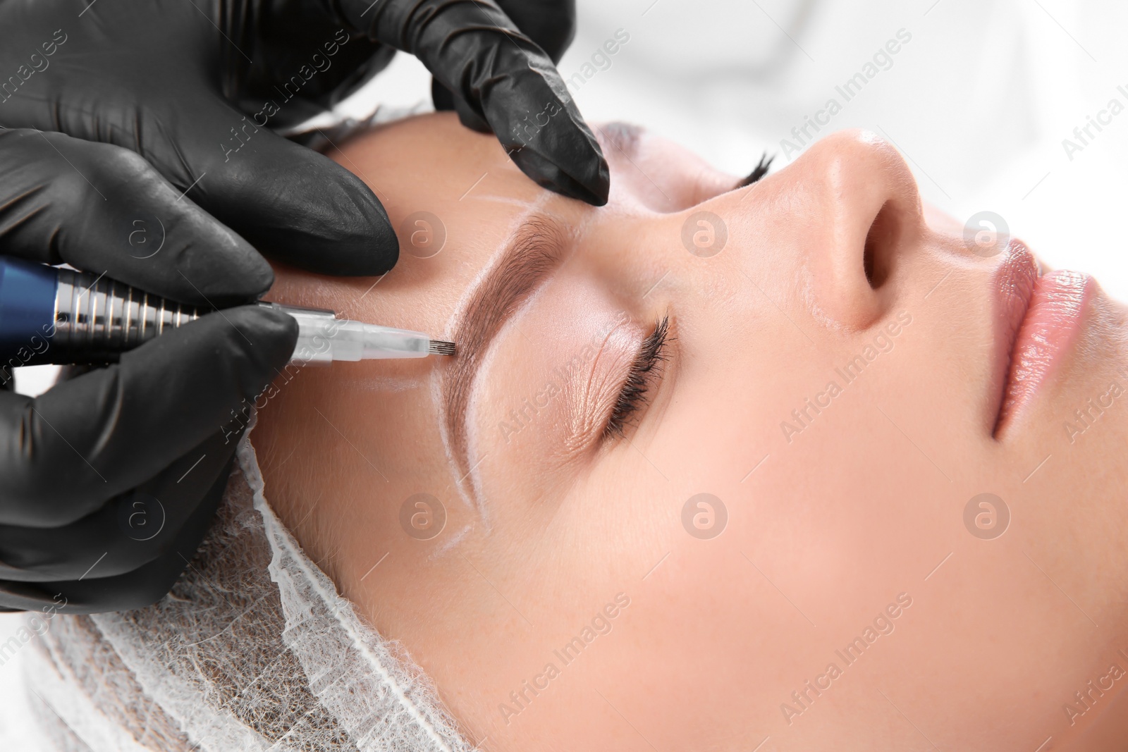 Photo of Young woman undergoing eyebrow correction procedure in salon