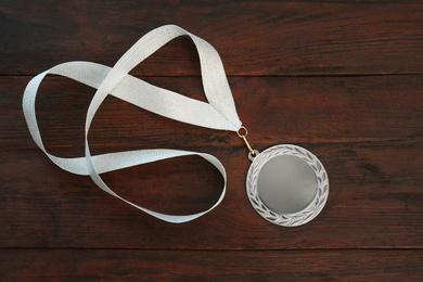 Photo of Silver medal on wooden background, top view. Space for design