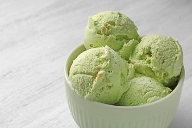 Photo of Tasty pistachio ice cream on white wooden table, closeup view. Space for text