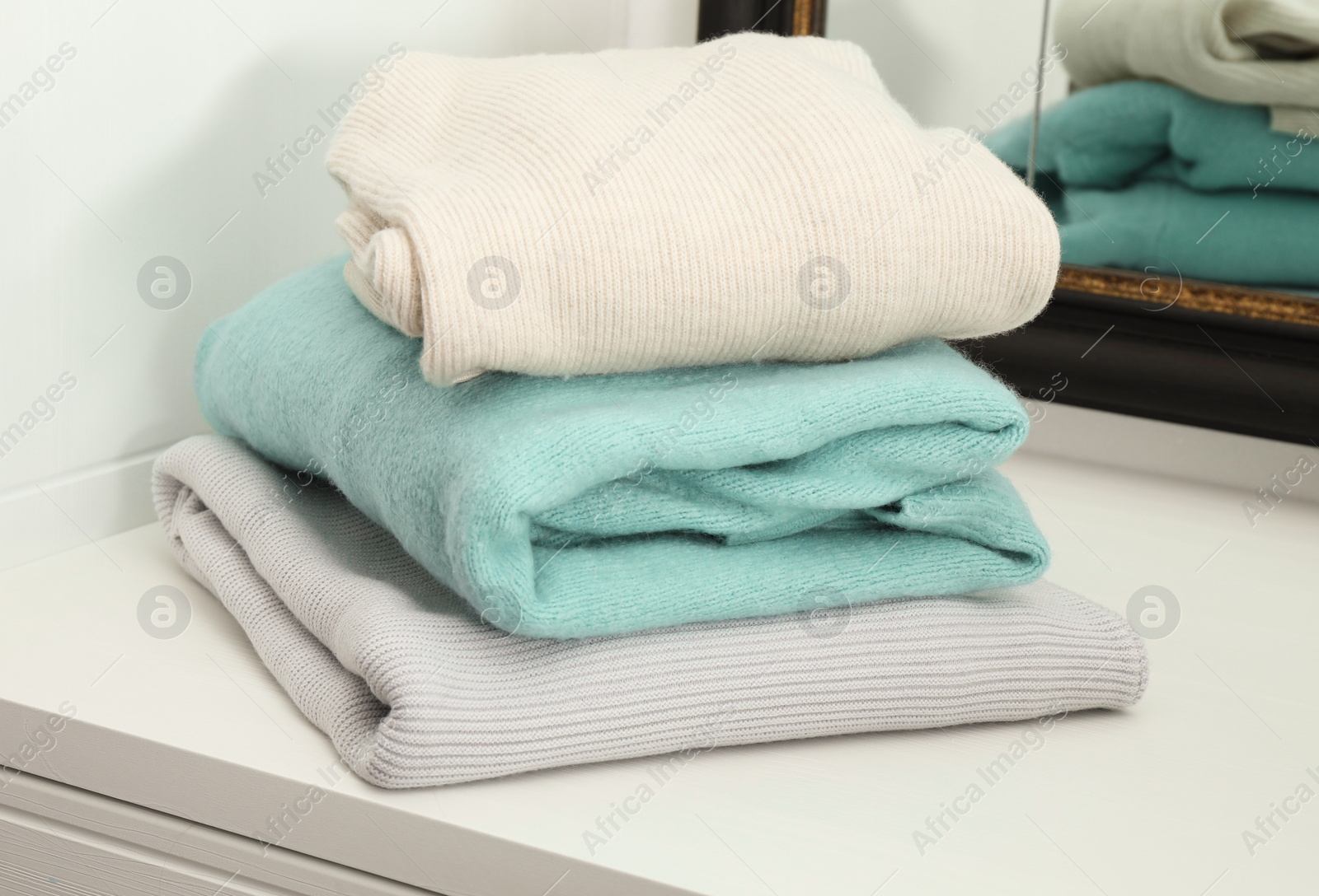 Photo of Stack of folded clothes on cabinet indoors